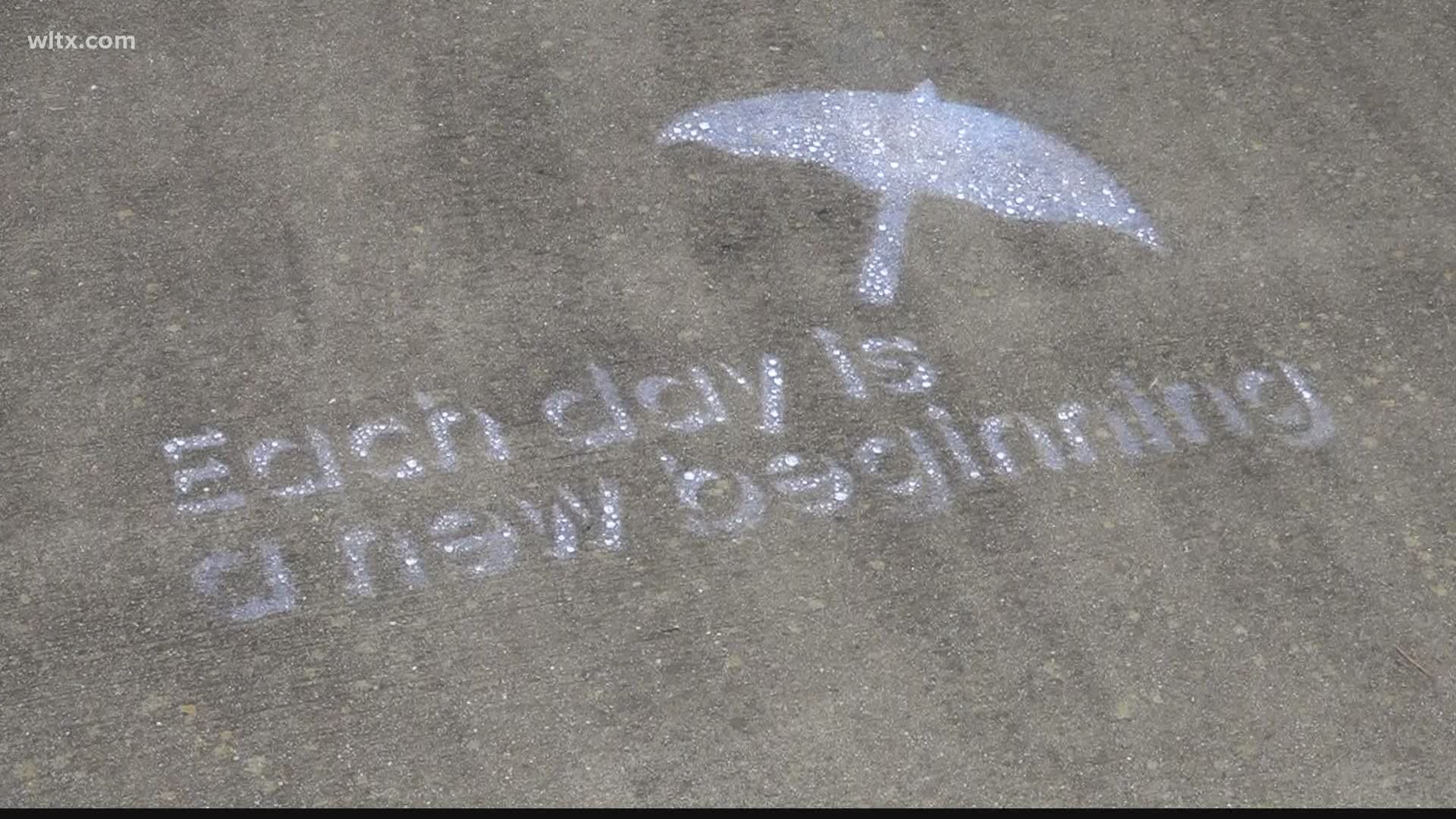The art, on the sidewalks in Newberry, can only be seen when it rains or when the pavement gets wet.