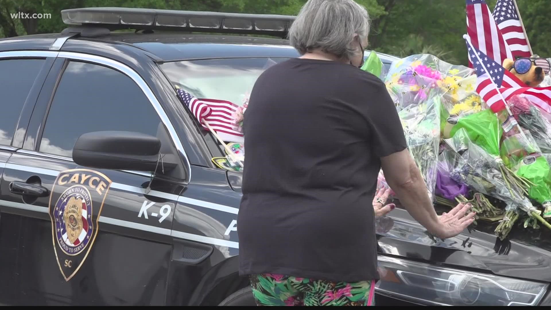 At police headquarters, Barr's patrol vehicle has turned into a memorial. Flowers, notes, and gifts are displayed on the hood.