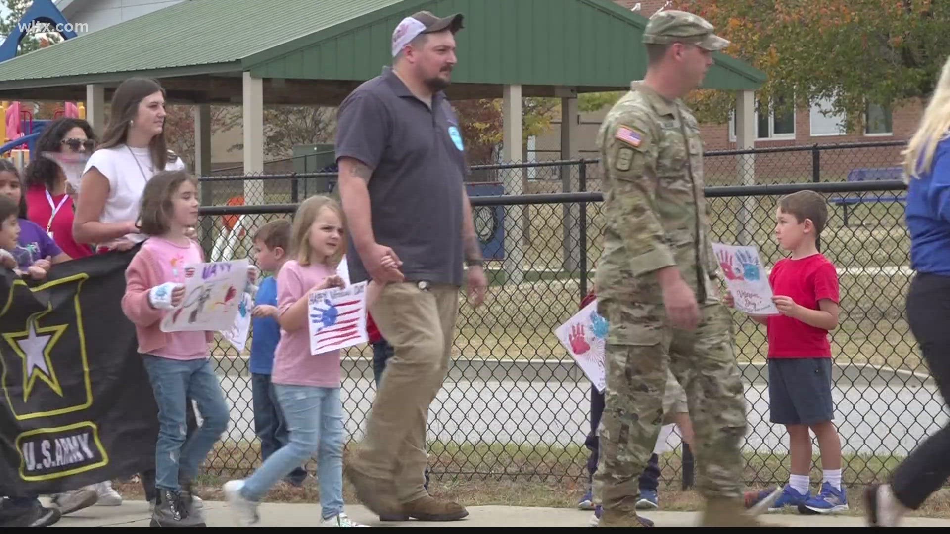 The elementary school greeted veterans with handmade signs and posters and led the parade with flags.