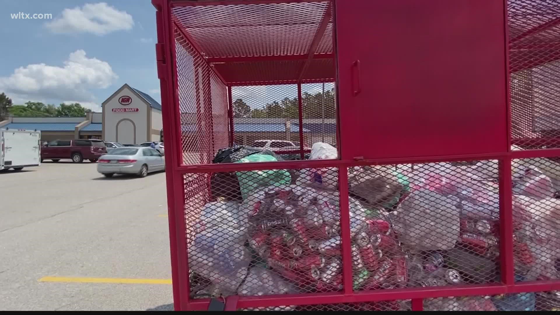 Several large red containers are filled with cans as part of an effort to raise money for the South Carolina Burned Children's Fund.